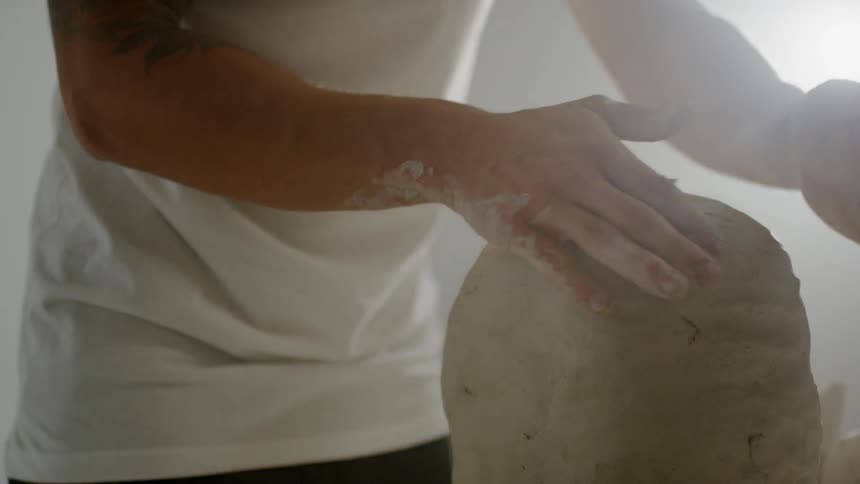 Person molds a lump of clay into a head shape