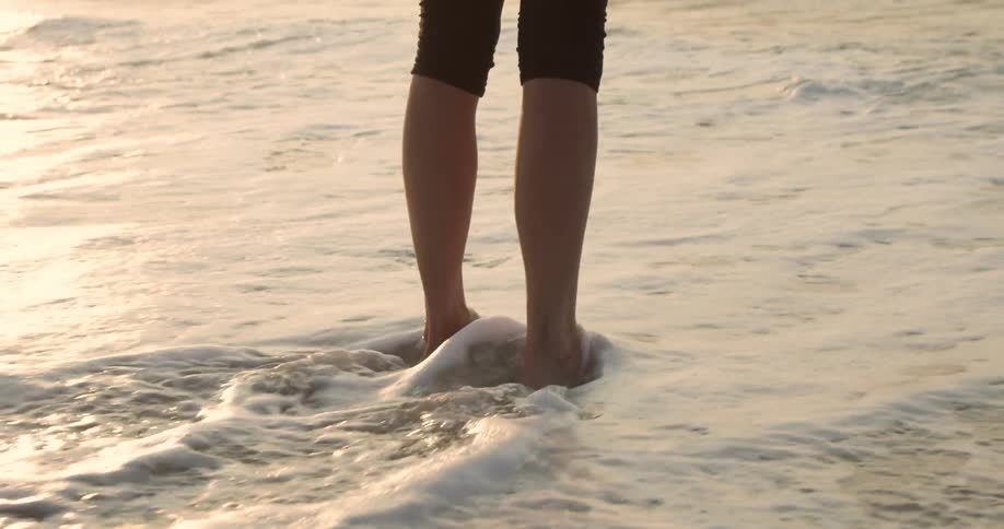 Waves wash over a person's bare feet