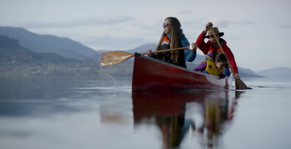 A family canoes on a mountain lake