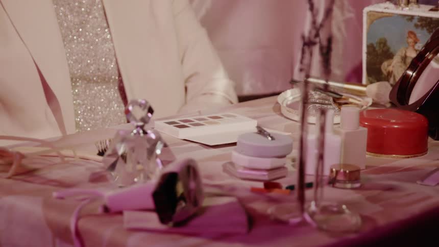 A woman sits at a makeup table