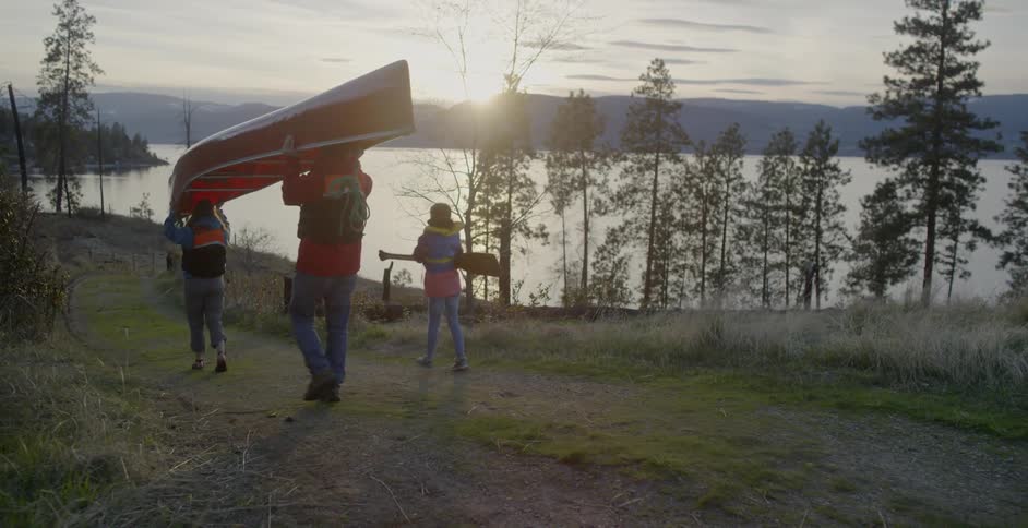 A family canoes at a mountain lake at sunset