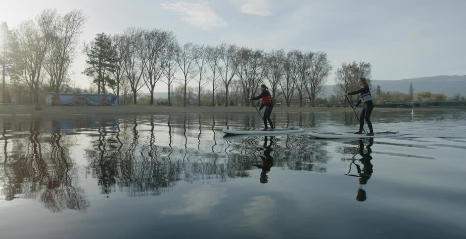 Two people paddle board on the water
