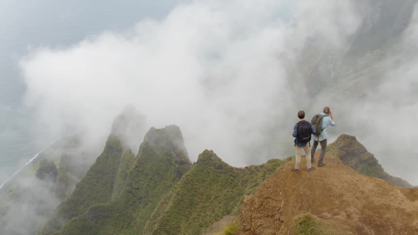 Hikers stand on a mountain peak overlooking a beach