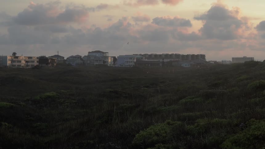 Sun sets over several buildings in a field