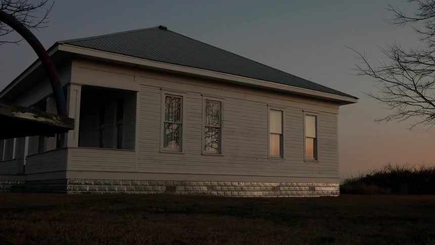 A swing is swaying in the breeze outside a house at dusk