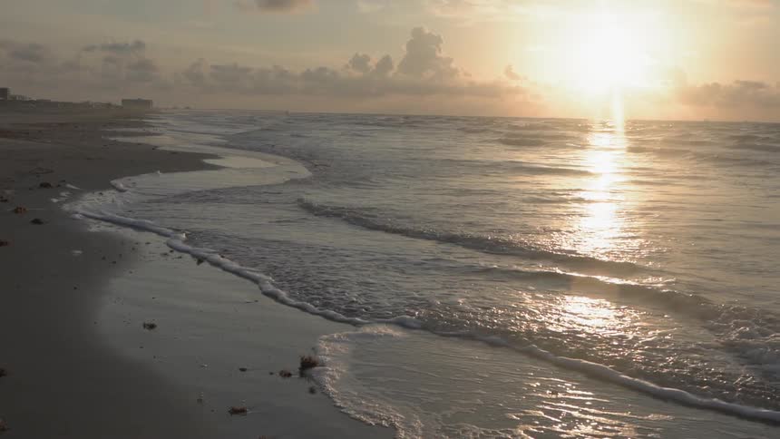 The sun sets over waves on a beach