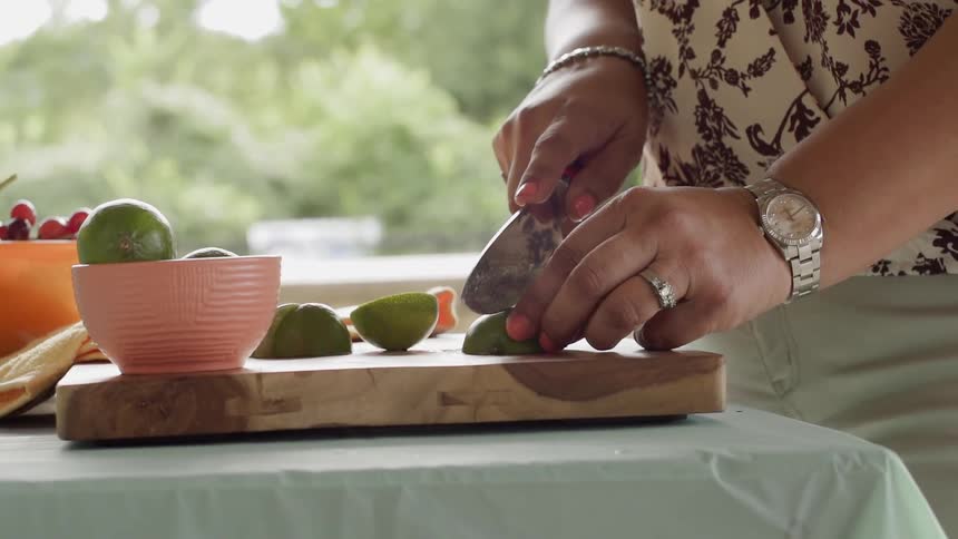 A woman cuts limes on a cutting board