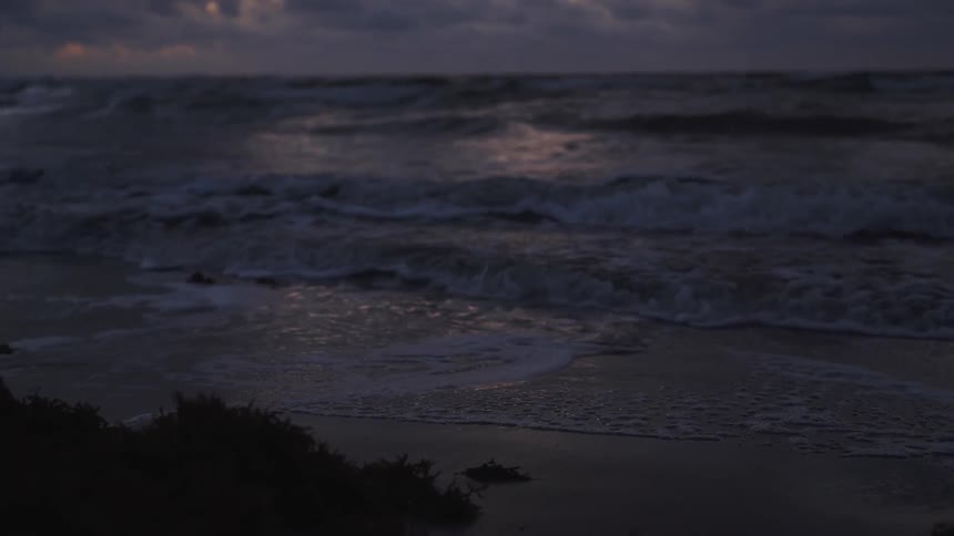 Waves roll in to shore under the dark clouds
