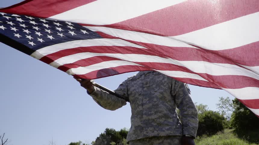 A soldier is waving the american flag