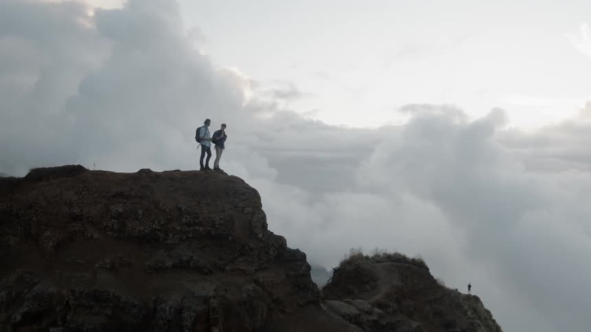 Two men stand atop a mountain