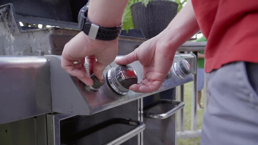 Man adjusts the dials of a barbecue
