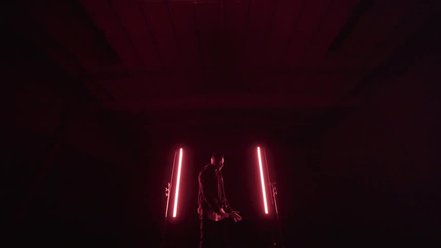 Man performs on a stage with lights on each side