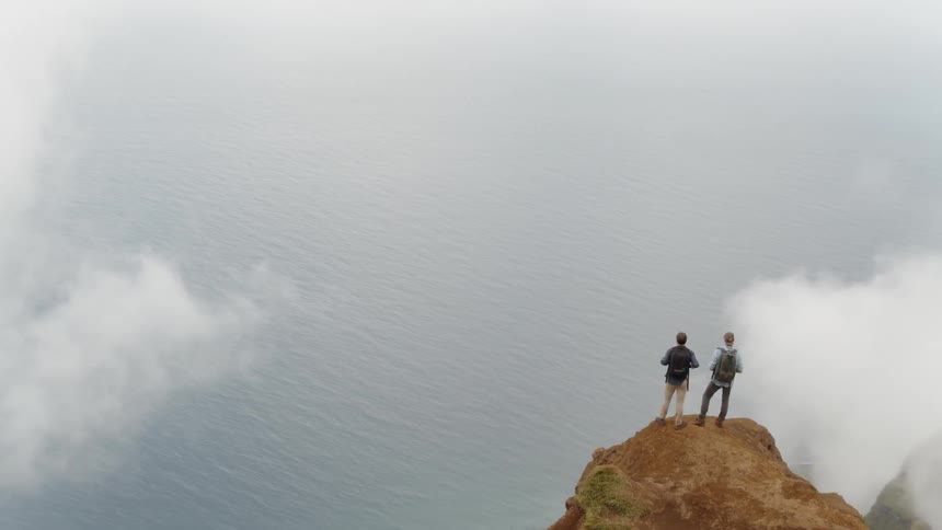 Two men stand atop a mountain