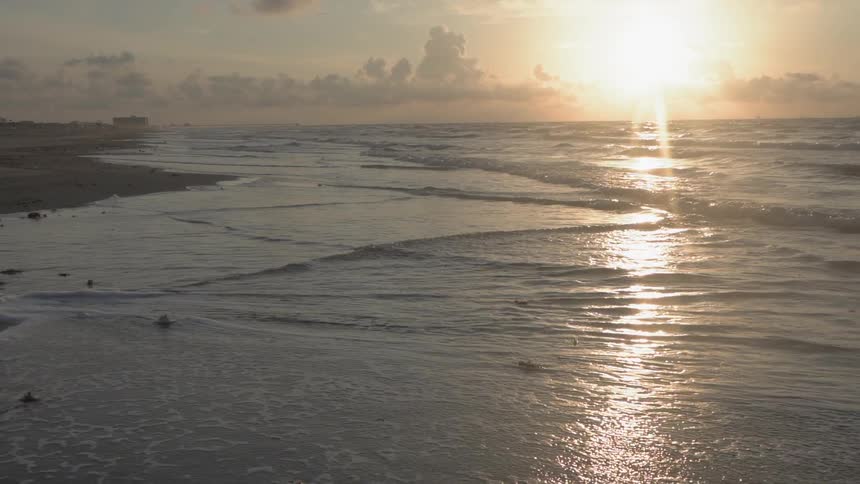 Ocean waves flowing onto beach as sun sets