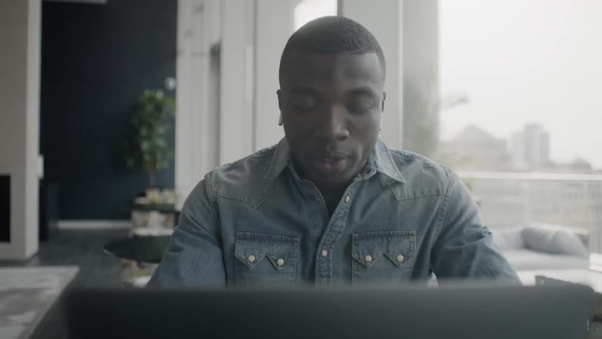 A man talks and types on a laptop