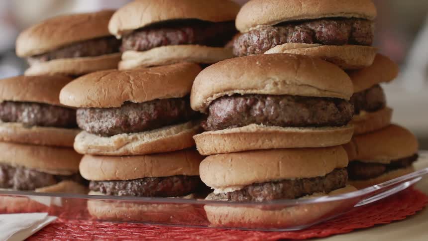 A large stack of burgers sit on the plate