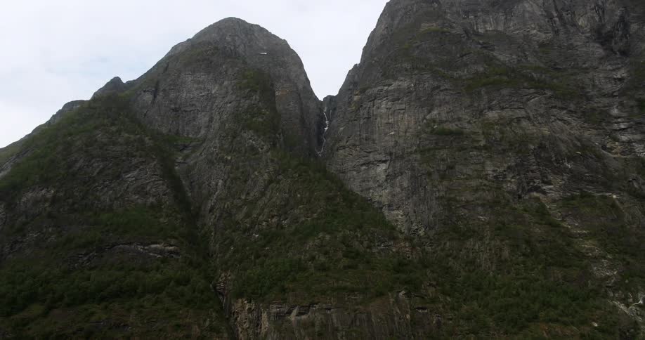 A bird flying below some large rocks