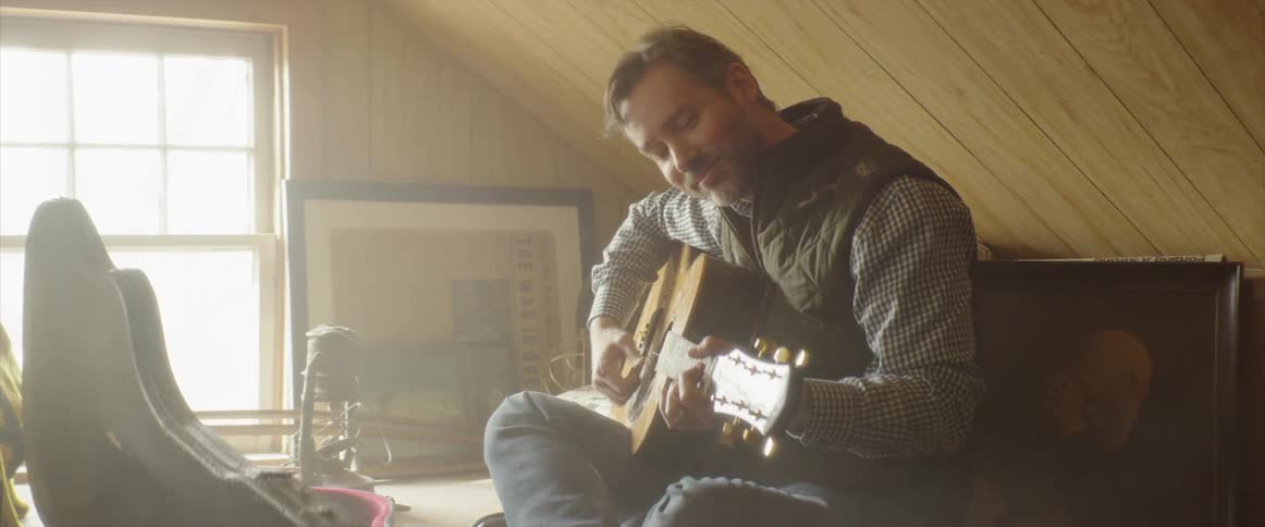 Man plays a guitar under a slanted roof