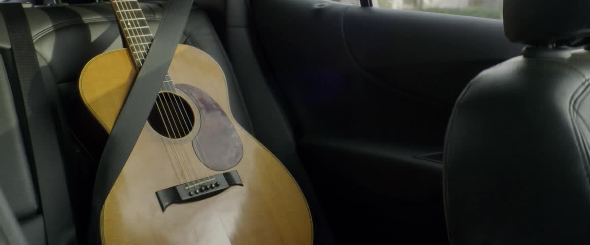 Seat belt holds a guitar in place as the vehicle travels