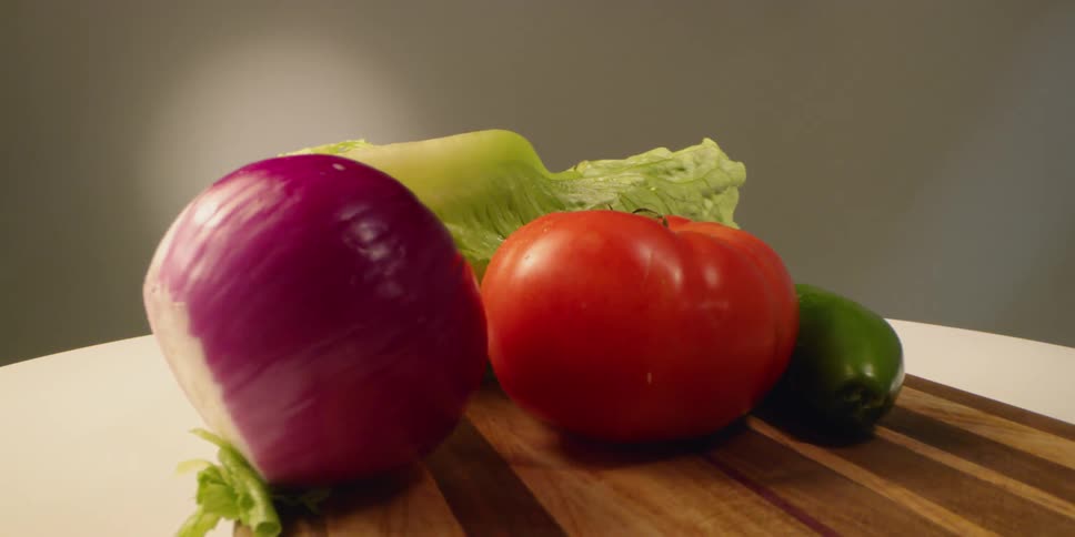 Vegetables sit on a cutting board in daylight