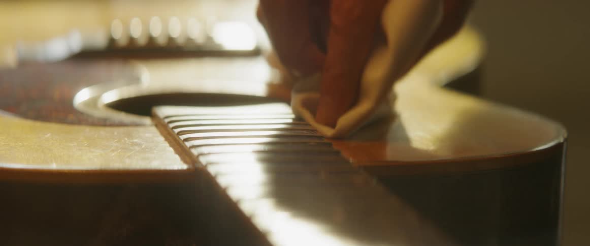 A person is wiping down a guitar