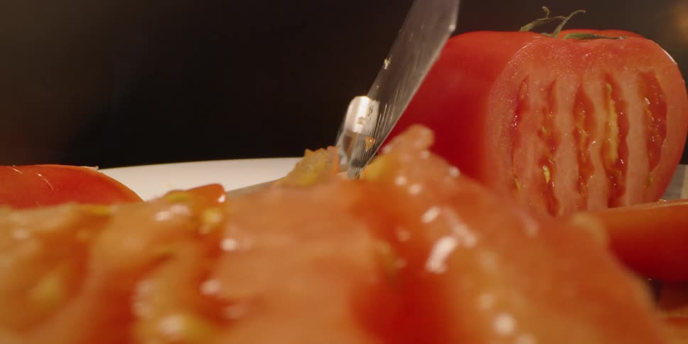 Knife and slices tomato on chopping block