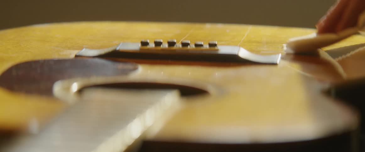 Person wipes off acoustic guitar