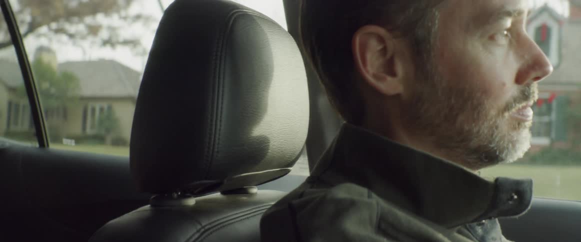 Guitar is buckled into back seat of mans car