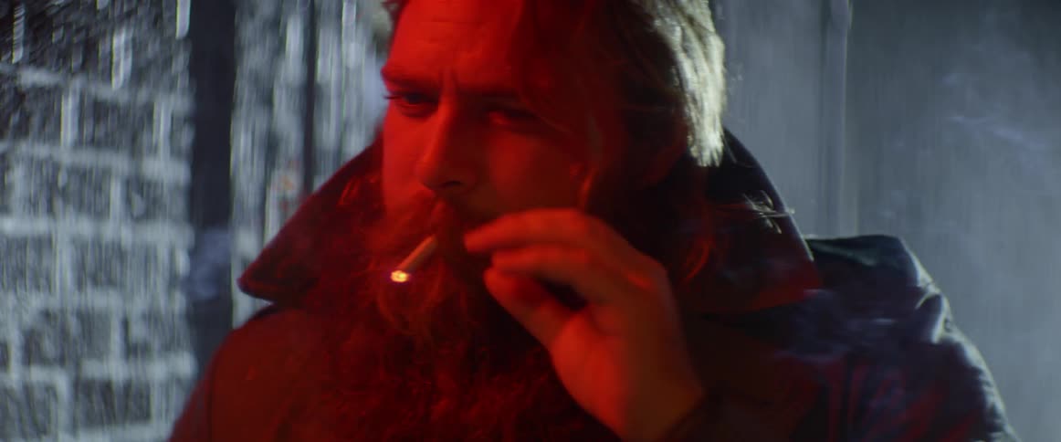 A man smokes a cigarette outside while it rains