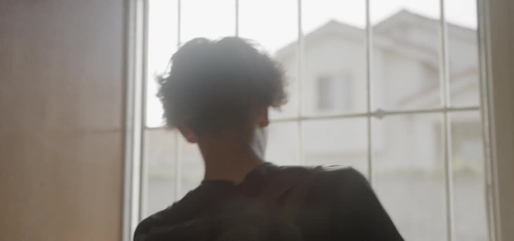 A boy exits the house on a sunny day