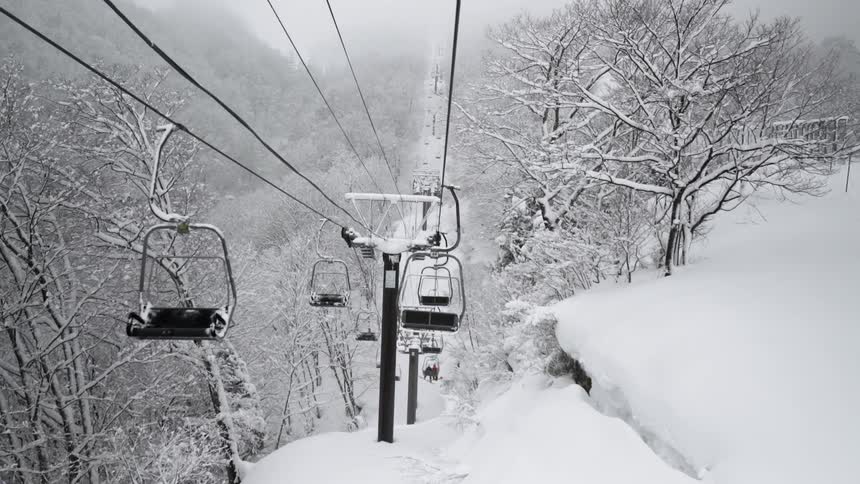 Empty ski lifts go up and down a mountain