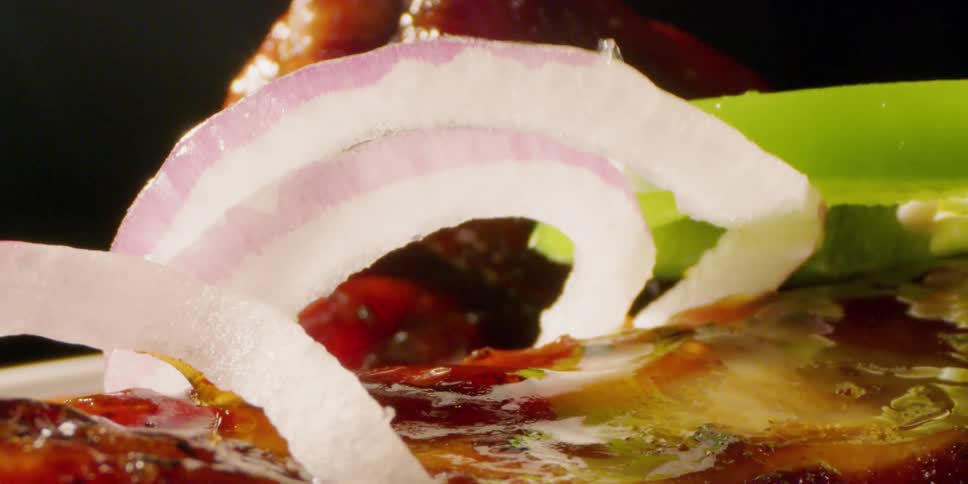 Onions and pickles are dropped on barbecued meat