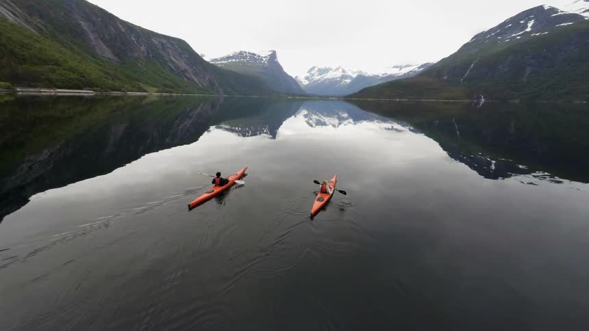 Two kayakers paddle on a mountain lake
