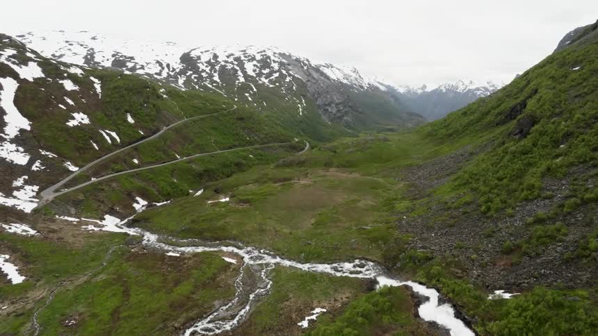 A stream runs through the snow-topped mountains