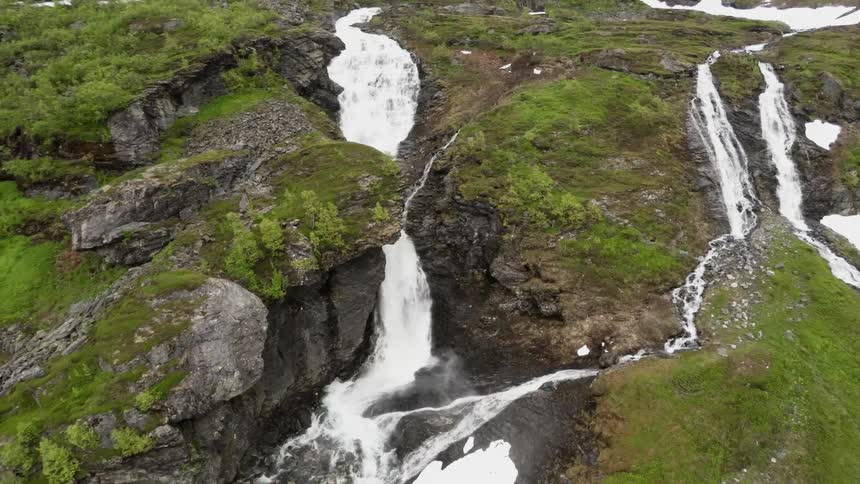 A waterfall flowing down large cliffs that are moss covered