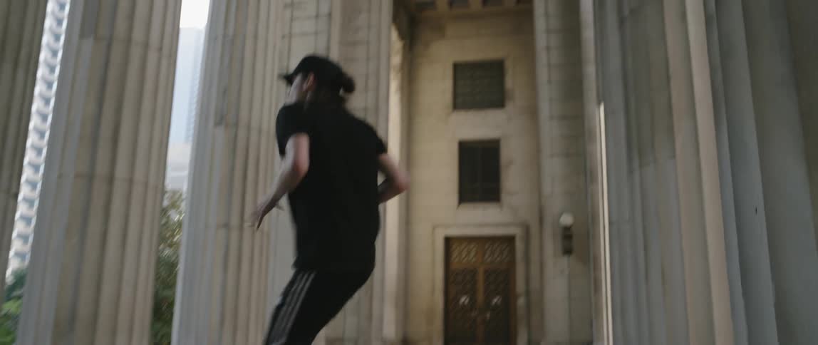 Woman wearing a hat does dance moves near the pillars
