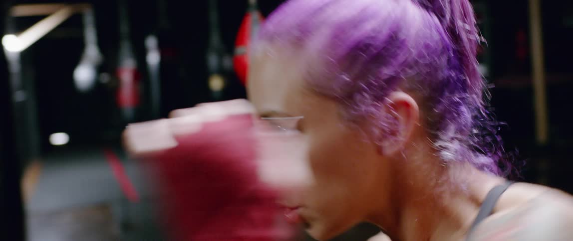 A woman is shadowboxing in the gym in front of a mirror