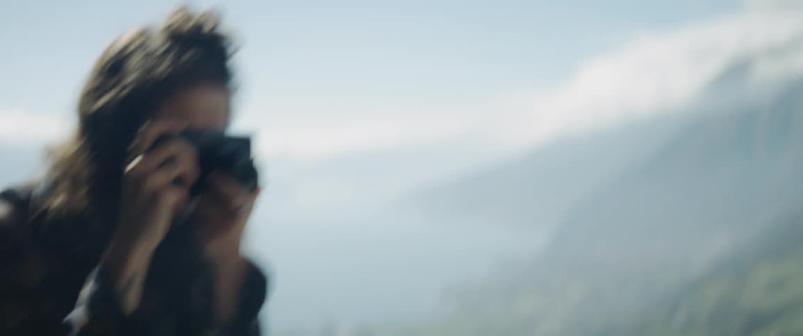 A woman is photographed on top of a mountain