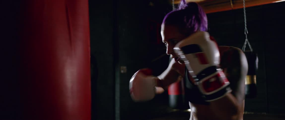 A woman is punching a heavy bag