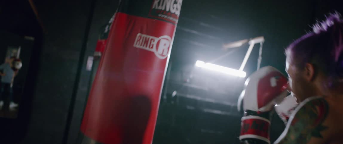 The woman is punching the red heavy bag