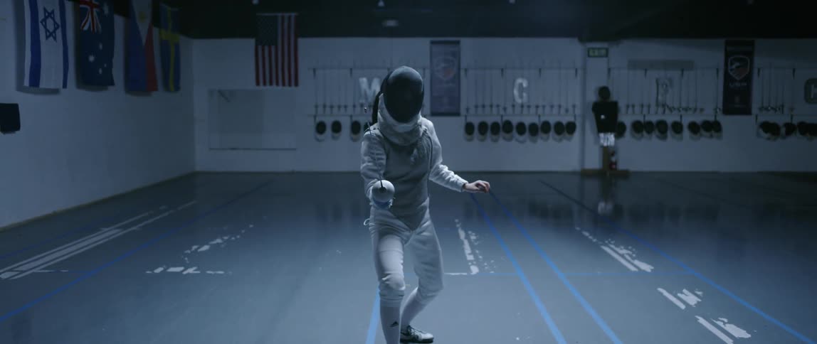 Woman practices fencing in an indoor arena