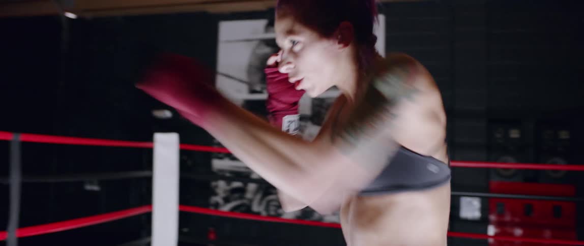 Woman stands in a boxing ring practicing punching