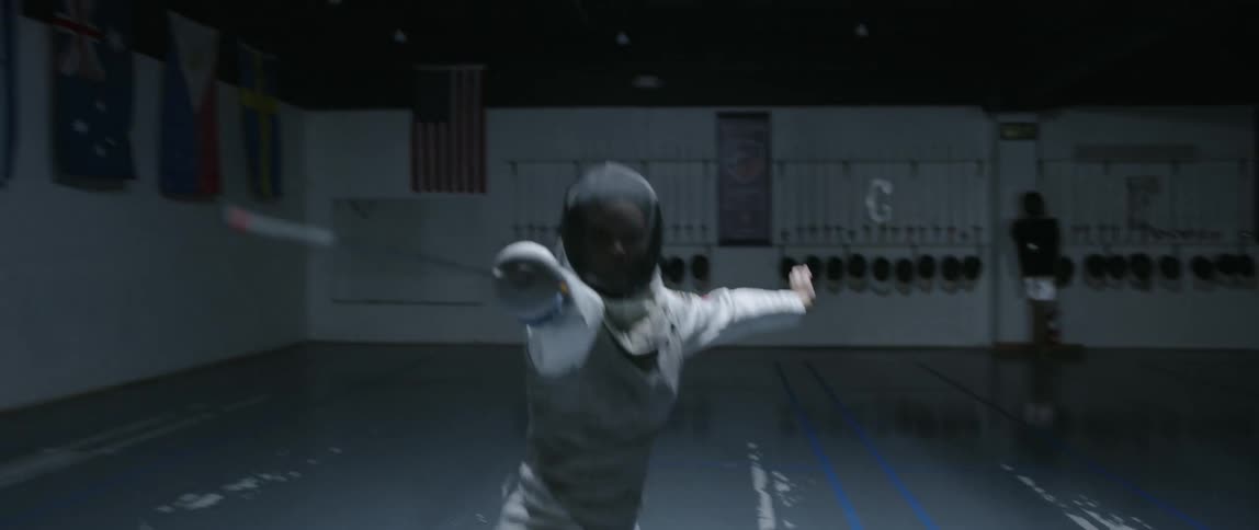 Person practices fencing in an indoor arena