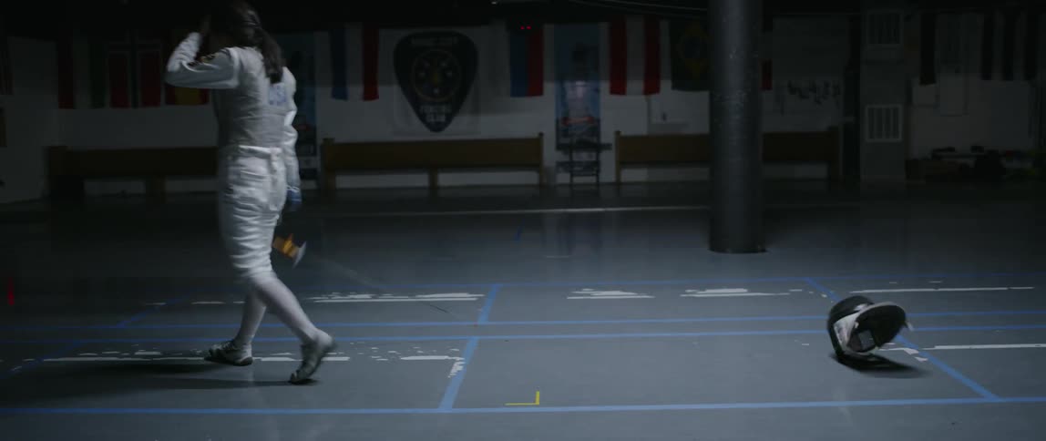 A fencer lunges forward then throws her helmet off
