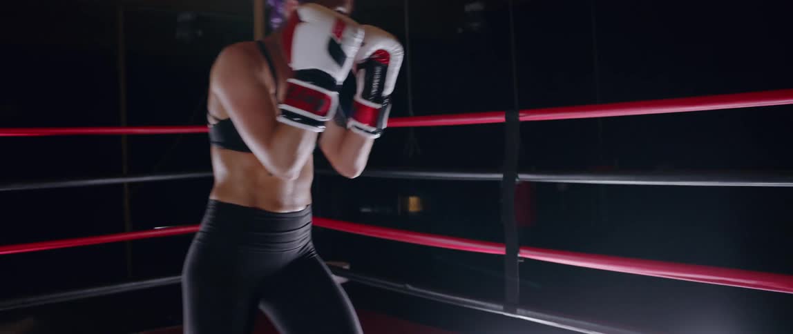 Woman practices punching in a boxing ring