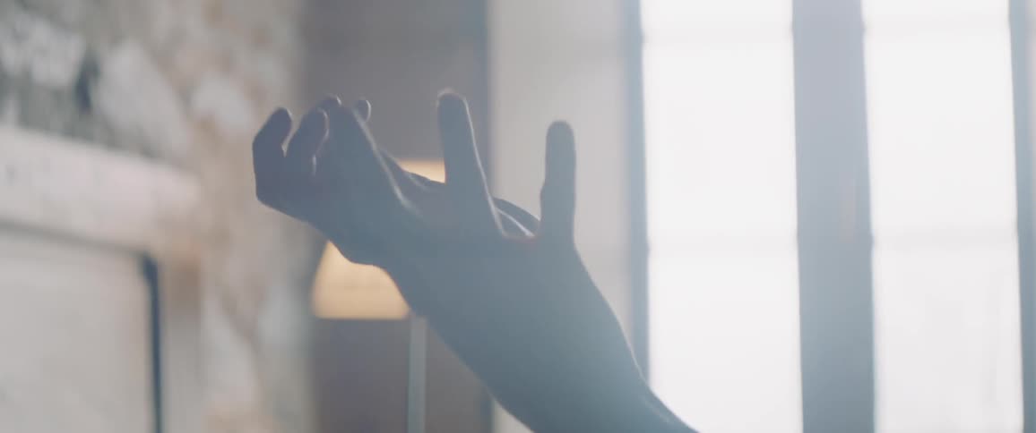 Woman laying in bed raises her hands in the air