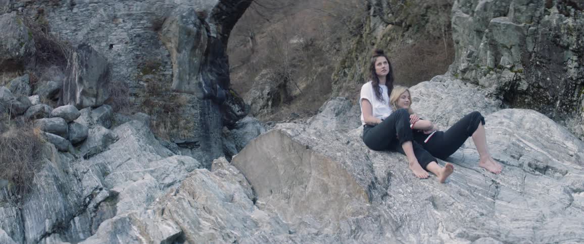Two women sit on the rocks together