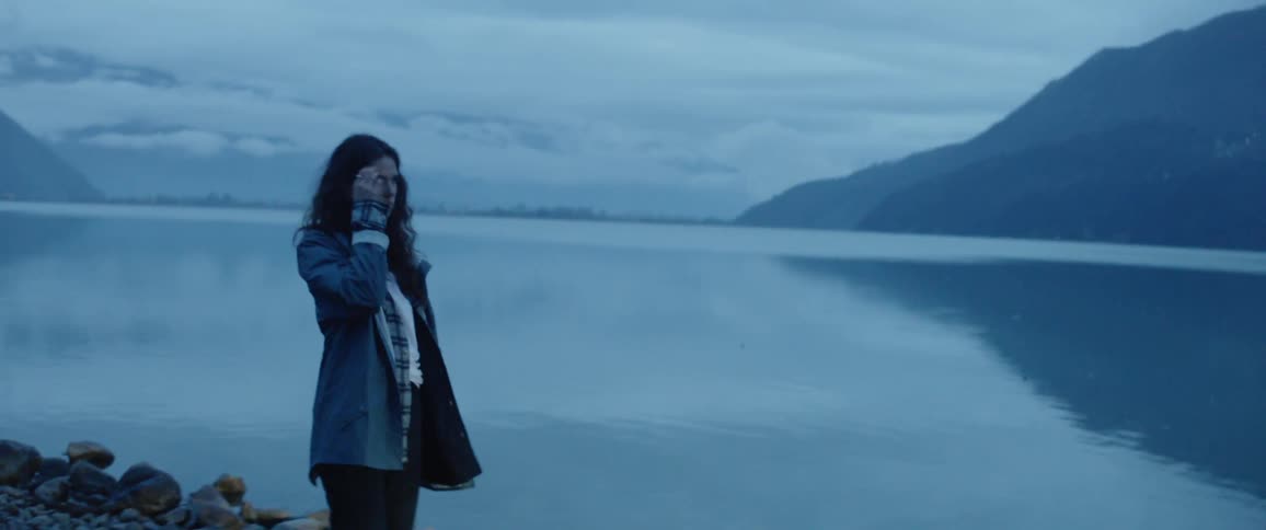 Woman gets out of a car and looks out over a lake