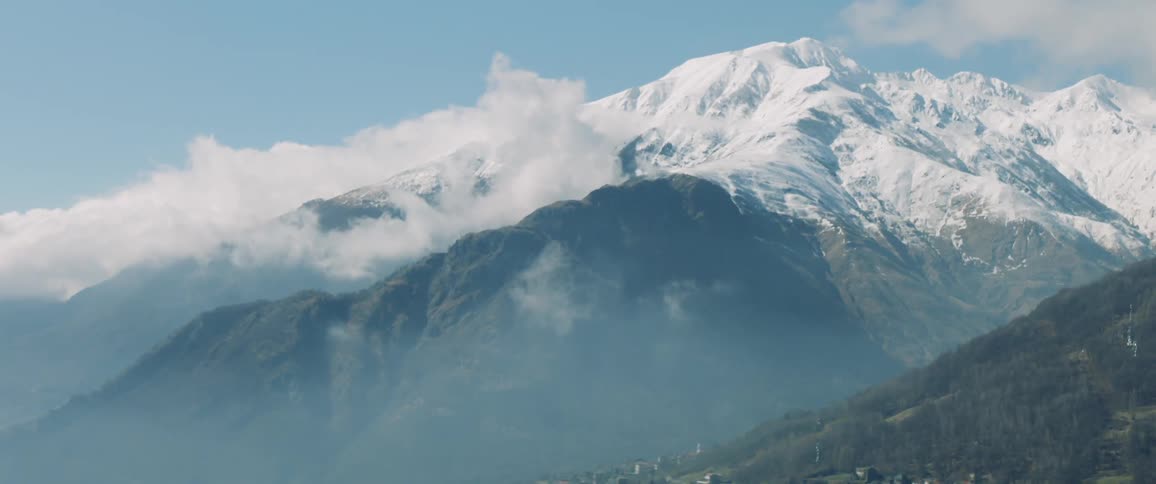Clouds touch snow covered mountain