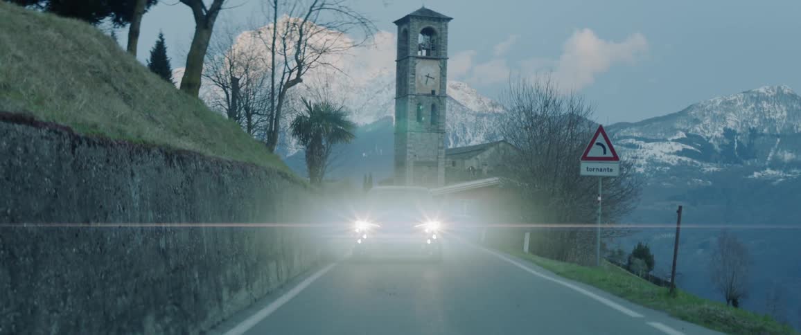 Clock tower in a rural area with a car driving by
